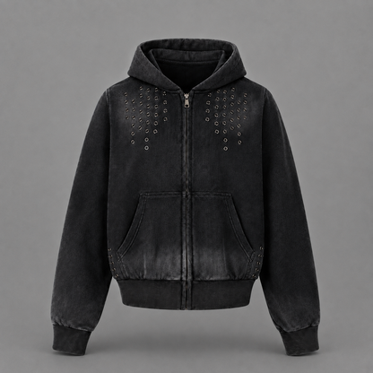A black washed zip-up hoodie jacket with silver metal studs arranged in vertical rows on the chest, shown against a solid gray background.